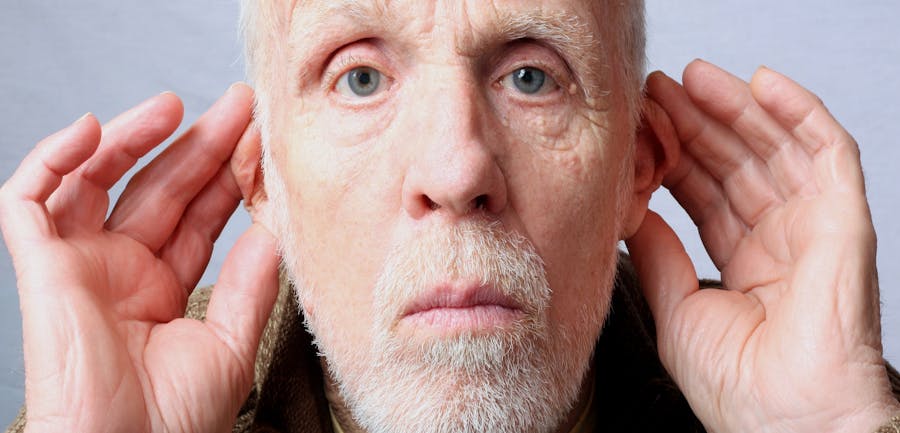 Older man with his hands on his ears