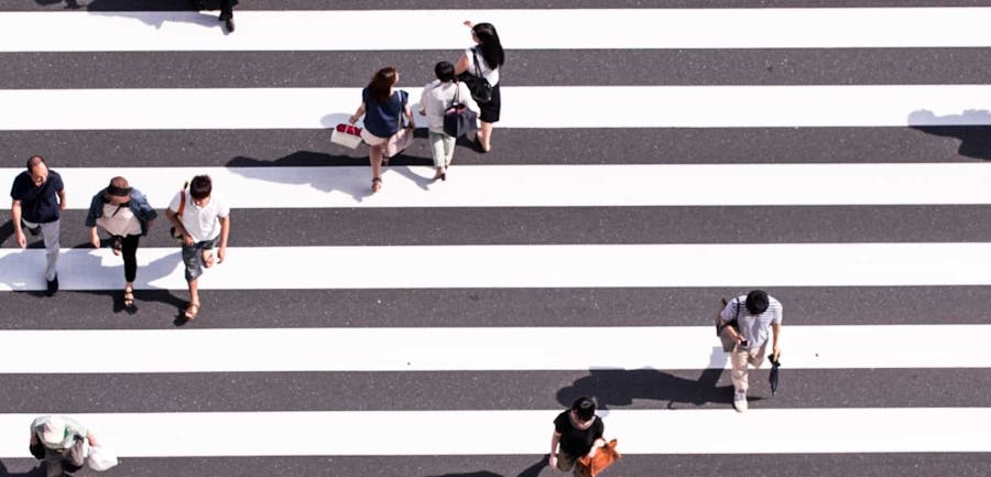 Overhead view of people walking on a crosswalk with white stripes